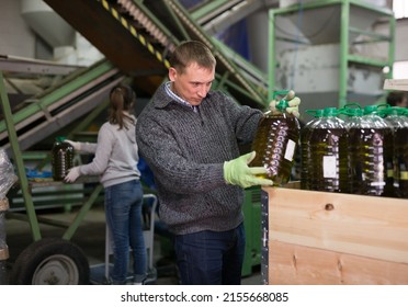 Successful owner of small olive oil factory working at warehouse, checking plastic bottles filled of finished product .. - Powered by Shutterstock