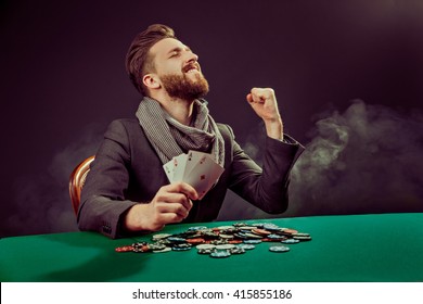 Successful poker player enjoying his win at poker table with chips and cards - Powered by Shutterstock