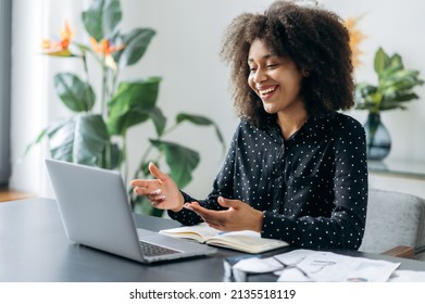 Successful positive young adult woman african woman freelancer, manager, CEO, sitting in office at laptop, talking on video call with client or employees, discussing business strategy, gesturing,smile