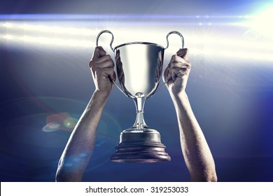 Successful rugby player holding trophy against spotlights - Powered by Shutterstock