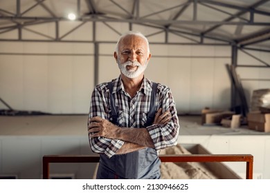 Successful senior factory workers. A proud successful smiling senior factory worker in working uniform is standing in the factory with arms crossed. - Powered by Shutterstock