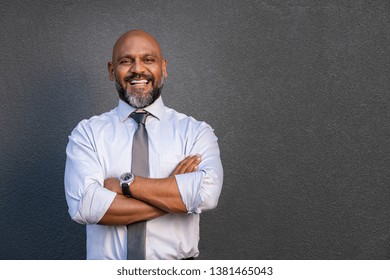 Successful Senior Man With Folded Arms Standing Over Grey Background. Mature Black Businessman In Shirt And Tie Looking At Camera. Portrait Of Joyful Business Man On A Grey Wall With Copy Space.