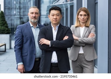 Successful And Serious Diverse Team Of Three Business People, Man And Woman Focused Looking At Camera With Arms Crossed, Portrait Of Co-workers Outside Office Building