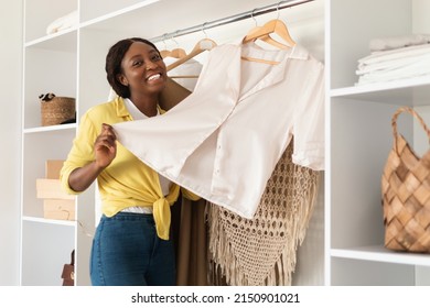 Successful Shopping. Happy African American Woman Posing With Garment Buying New Trendy Clothes In Store Standing Indoor, Smiling To Camera. Fashion And Style Concept - Powered by Shutterstock