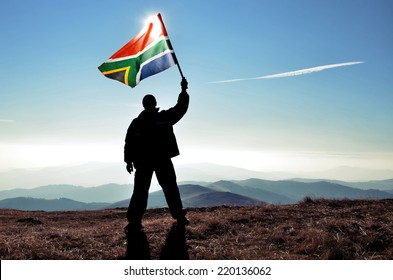 Successful Silhouette Man Winner Waving South African Flag On Top Of The Mountain Peak