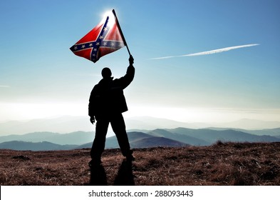 successful silhouette man winner waving Confederate flag on top of the mountain peak