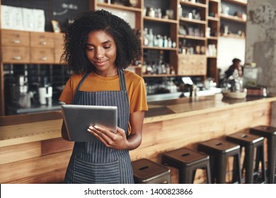 Successful Small Business Owner Using Digital Tablet In Her Cafe