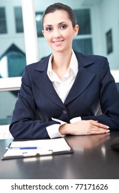 successful, smiling business woman in her office, looking in camera