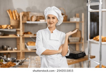 Successful smiling female baker in white chef uniform, making welcoming gesture with hand in cozy bakery kitchen surrounded by freshly baked bread and pastries arranged on shelves - Powered by Shutterstock