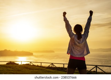 Successful sporty woman raising arms towards golden beautiful sunset and sea. Female athlete celebrating sport success and goals. Healthy lifestyle and freedom concept. - Shutterstock ID 238537666