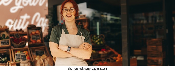 Successful supermarket owner smiling at the camera while standing in the fresh produce section of her grocery store. Happy young woman running a small business in the food industry. - Powered by Shutterstock