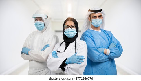 Successful team of Arabic medical doctors are looking at camera while standing in hospital with arms crossed male and female doctors in protective gear fighting coronavirus COVID-19. - Powered by Shutterstock