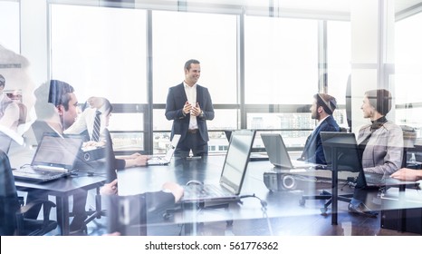 Successful team leader and business owner leading informal in-house business meeting. Businessman working on laptop in foreground. Business and entrepreneurship concept. - Shutterstock ID 561776362