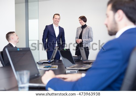 Successful team leader and business owner leading informal in-house business meeting. Businessman working on laptop in foreground. Business and entrepreneurship concept.