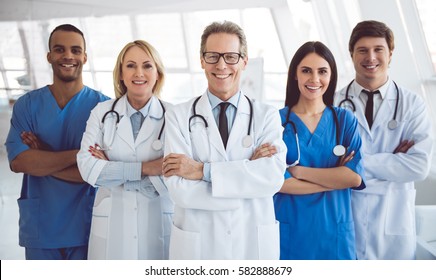 Successful Team Of Medical Doctors Are Looking At Camera And Smiling While Standing In Hospital