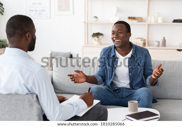 Successful\
Therapy. Cheerful black man talking to psychologist on meeting at\
his office, sharing his progress with\
doctor