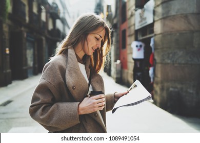 Successful travel blogger happy to see her name mentioned on a city newspaper while walking down the street with a take away coffee. Fashion designer reading news about fashion week in the city. - Shutterstock ID 1089491054