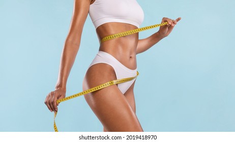 Successful Weightloss And Dieting. Closeup Of Slim Lady Measuring Waist With Tape, Happy About Her Body Parameters, Standing Isolated Over Blue Studio Background. Slimming Concept. Banner - Shutterstock ID 2019418970