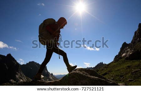 successful woman hiker with backpack hiking in sunrise mountains