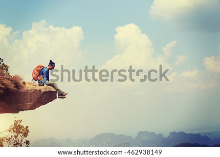 Successful woman hiker enjoy the view on mountain top cliff edge