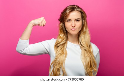 Successful woman raising hand in success gesture over pink background