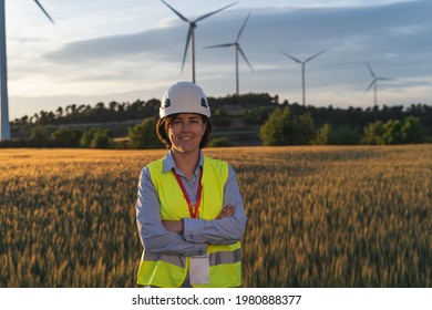 Successful Woman Wearing Safety Helmet And Working In Wind Farm Smiling And Looking At Camera.