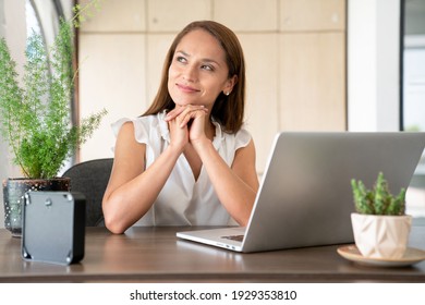 Successful woman working in office looking through the window pensive and positive.