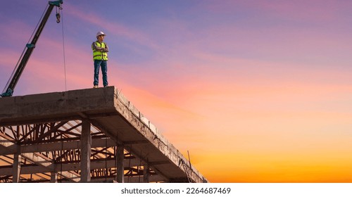 Successful Worker Wearing Hard Hat and Safety Vest Standing on  Building Construction Site Crane Machinery  and sunset sky Background,  - Powered by Shutterstock