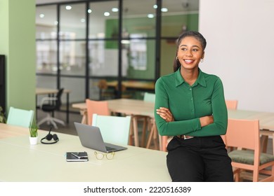 Successful young african-american female entrepreneur, small business owner, female office employee, black businesswoman wearing green casual shirt stands in confident pose with arms crossed - Powered by Shutterstock