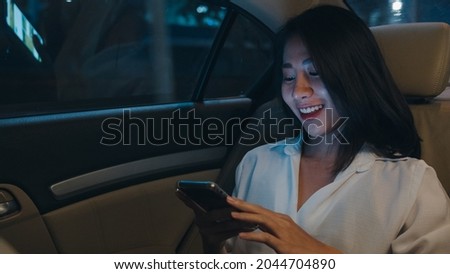 Successful young Asia businesswoman in fashion office clothes working late using smart phone in sitting back seat of car in urban modern city in night. People occupational burnout syndrome concept.