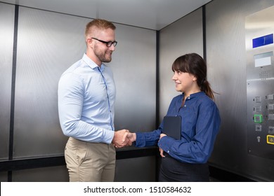 Successful Young Business Colleague In Formalwear Smiling And Shaking Each Other's Hand In The Elevator