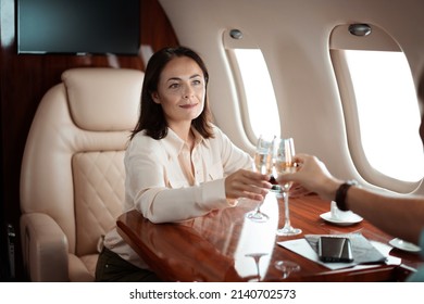 Successful young business woman traveler drinks champagne with her parthner during flight in private jet