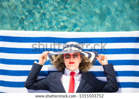 Successful young businesswoman on the beach. Woman lying on striped towel near swimming pool. Summer vacations and freedom travel concept