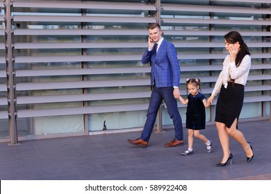 Successful young handsome male man young father and modern girl, young mother hold gadgets  in hand, mobile phones and talking on them, solve operational issues, agree to meet, negotiate with busines