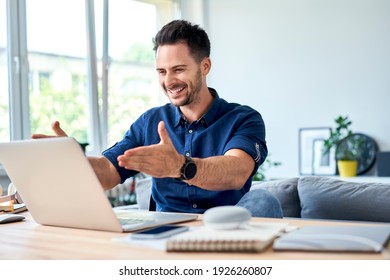 Erfolgreicher junger Mann, der bei der Arbeit im Heimbüro einen Laptop sucht