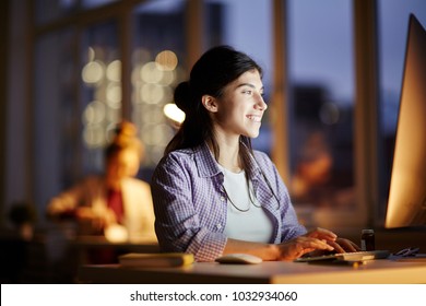 Successful Young Office Worker Sitting In Front Of Computer Monitor And Watching Webcast In The Evening