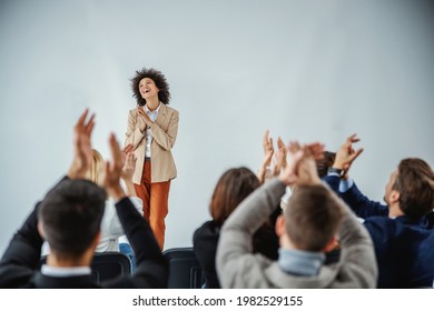 Successfully Completed Presentation. A Multicultural Group Of Businesspeople Cheering And Applauding A Curly Mixed-race Entrepreneur Who Has Just Finished Her Speech On Stage