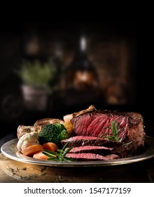 Succulent side of rare roast beef with seasonal vegetables, Yorkshire Puddings and roast potatoes with Rosemary garnish shot in a rustic setting with an old fashioned wood burner. Copy space. - Shutterstock ID 1547177159