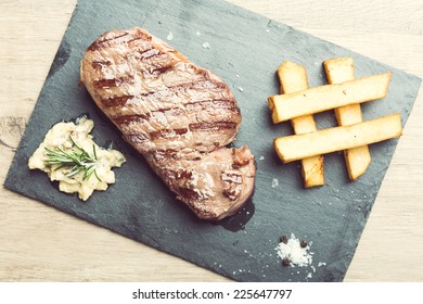 Succulent thick juicy portions of grilled fillet steak served with potatoes and sauce of mushrooms on a slate plate 