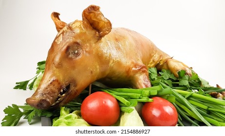 a suckling pig or pig roasted on a spit or in the oven lies on a tray. festive pork dish decorated with vegetables on a white background.