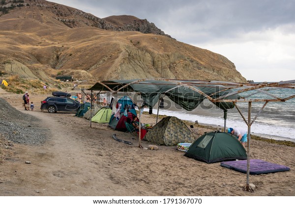 Sudak,\
Crimea, Russia - September 7, 2018: A small tent camp on the Black\
Sea coast against the background of Cape\
Meganom