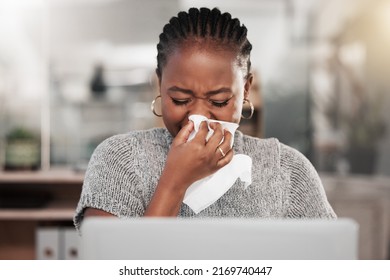 And Suddenly It Was Flu Season. Shot Of A Young Businesswoman Blowing Her Nose And Using A Laptop In A Modern Office.