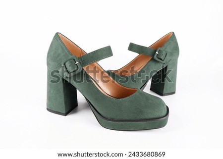 Suede women's green shoes with a strap and buckle on a high thick heel and platform on a white background.Sale of stylish shoes.Workshop for the repair and care of suede and nubuck shoes.