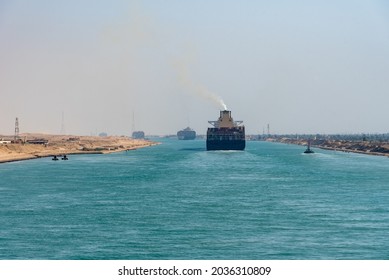 Suez Canal, panorama view of the canal with blue water and transiting ship on the horizon.   - Shutterstock ID 2036310809