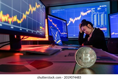 Suffer Unsuccessful Broker Trader Sit Stress Depressed At Working Office Desk In Trading Room Hold Hand On Head While Stock Market Chart On Screen Decrease With Bitcoin In Foreground.