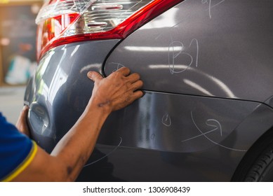 sufferer hand checking of vehicle car bumper dented broken from collision crash damage accident on road,checking cars for scratches and dents