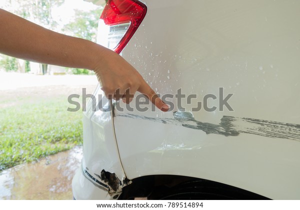 sufferer hand point of vehicle car bumper dented\
broken from collision crash damage accident on road,checking cars\
for scratches and\
dents
