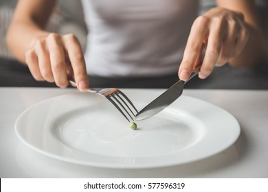 Suffering From Anorexia. Cropped Image Of Girl Trying To Put A Pea On The Fork