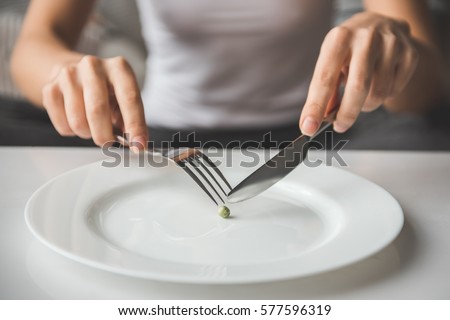 Suffering from anorexia. Cropped image of girl trying to put a pea on the fork Imagine de stoc © 