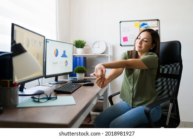 Suffering from carpal tunnel. Attractive young woman stretching her arms and wrists after finishing working on her home desk as a business manager 
